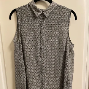 Ärmlös blus  - Tunn, ärmlös, semigenomskinlig, mönstrad ljusblå blus med krage från H&M. Längre i ryggen och i fint skick. Köparen står för frakt. Hojta för fler bilder. ✅ 