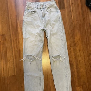 Jeans - Ljusblåa 90s high waist jeans med hål ifrån ginatricot, storlek 32. Använda nån enstaka gång. Säljer för 80kr plus frakt🥰