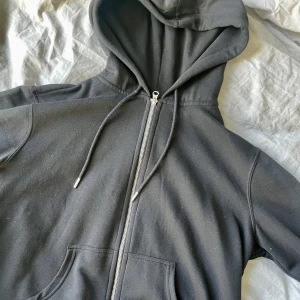 Svart ziphoddie - Svart zip up hoddie. Superbra basplagg som funkar till allt. Tröjan har en mörkare svart färg i verkligheten.