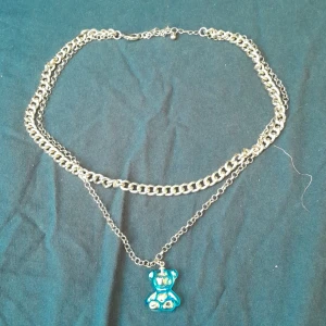 Halsband - Guldigt halsband. Inte äkta. Med en blå holographic björn som smycke