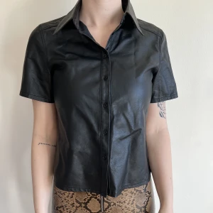 T-shirt i skinnimitation - T-shirt i skinnimitation från Nelly, storlek 36. 