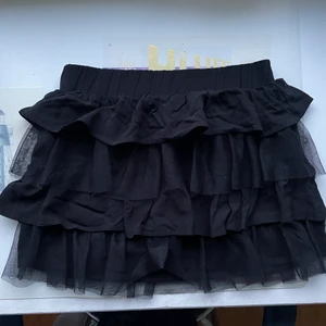 Lågmidjad kortkjol Kappahl  - En svart lågmidjad kortkjol som som aldrig kommer till användning. Det finns inga slitningar eller tecken på användning. Storleken är 158/164 vilket motsvarar ungefär XS/S. Volangerna är i vanligt tyg och mesh.   Hör av dig vid intresse!😊