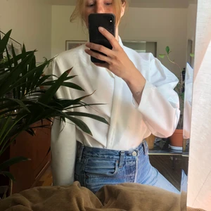 Vit blus / kavaj  - Vacker blus/kavaj med subtilt mönster i väven. Puffiga axlar och öppen fram. Tänker fint att knäppa med en brosch. Tyget är av det grövre slaget, ev siden?   Storlek funkar på S-M ungefär   Finns i Årsta men kan skickas mot porto 