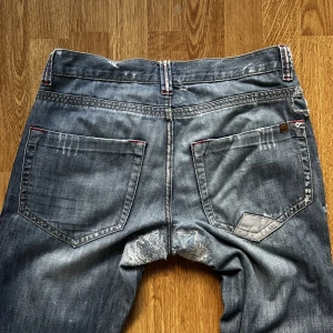 Y2K Ironcat Jeans - (Mått: W32, L34) super coola Y2K halvbaggy jeans i väldigt fint skick. Ett hål som fanns under skrevet har lappats igen super snyggt. Färgen är mörk gråblå. Kan mötas upp eller frakta via Postnord