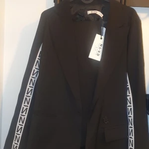 Kostym set  N Branded Blazer black/white  - Elegant kostym set från NA-KD (N Branded Blazer) black/white. Köptes innan graviditet men tyvärr har ej hunnit använda dem. Köpte dem separat ordinarie pris Blazer= 449kr byxor=549kr fler bilder finns att kolla på.