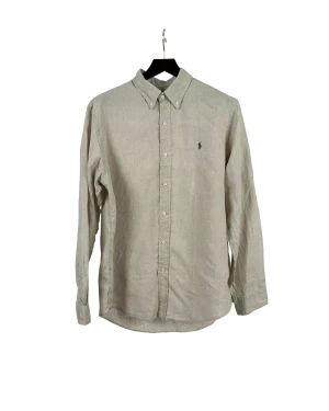 Beige linne skjorta - Linne skjorta från Polo Ralph Lauren i en beige färg.   Plagget har en rak passform.   Mått, i cm: Bröst: 130 Midja: 122 Stuss: 128 Rygglängd: 84 Ärmlängd: 68