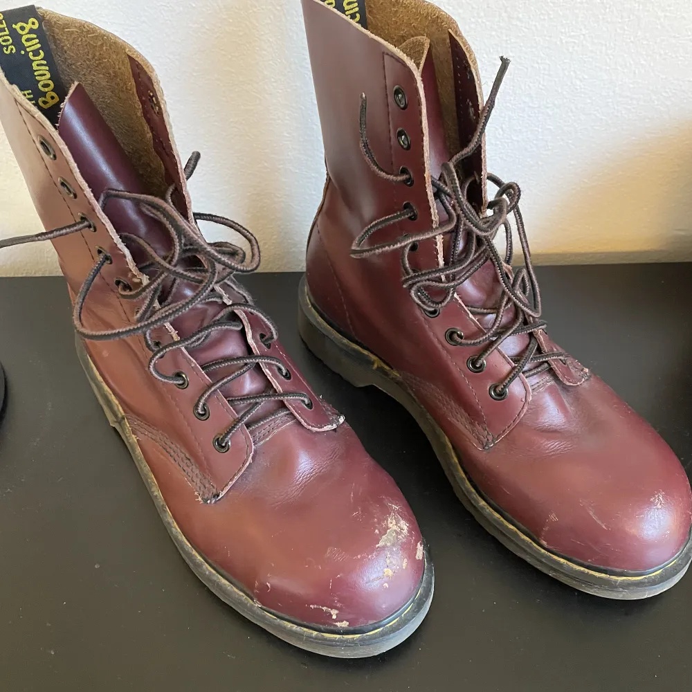 Begagnade höga vintage Dr martens i rött! De är gjorda i England och har stålhätta. De är något slitna på höger sko men annars i ganska bra skick. Storlek 39/40.. Skor.