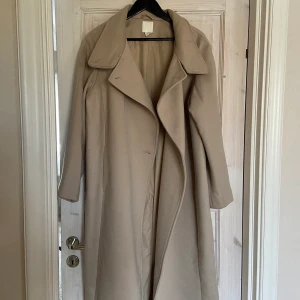Beige lång kappa  - En stilren långkappa i en ljus beige färg☺️ Jag är 165 cm och den går ner till vaderna på mig. Endast använd ett fåtal gånger.   Pris inkluderar frakt. Kan mötas upp i Stockholm🥰