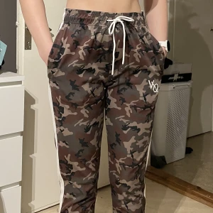 Vanquish byxa - Träningsbyxa i glatt material, både resår & snöre i midjan, fickor med dragkedja på båda sidorna. En ficka bak.  Använda fåtal gånger, i nyskick  