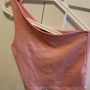 Oneshoulder linne - Så gulligt rosa linne. Oneshoulder. Passar perfekt till sommaren!! Storlek M men liten i storleken.