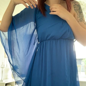 Blå klänning - Mörk blå klänning med ”vinge” på ena sidan och bar axlad på andra. Sååå fin men har tyvärr växt ut den. Strl S/36. Kan mötas upp runt Hässleholm/Kristianstad och även skicka den(köparen står för frakten)