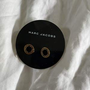 Örhängen från Marc Jacobs i guldplätering. Svart bakgrund med guld text där det står ”Marc Jacobs”. Aldrig använda. Nypris 600 kr.
