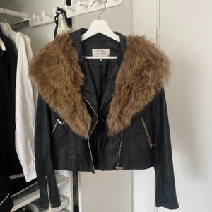 Skinnjacka Svart med Pälsdetaljer - Svart skinnjacka från River Island i skinnimitation/med fakepälsdetaljer, strl 36 (S), sparsamt använd så i väldigt bra skick, nyskick, går att plocka av/på pälsen så det blir som en helt vanlig svart skinnjacka