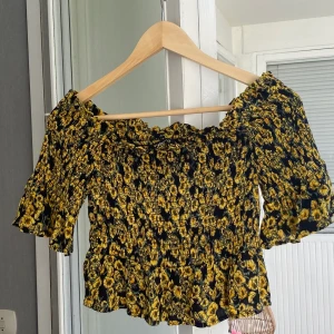 Söt topp med gula blommor  - Lite kortare i modellen och går att ha neddragen över axlarna eller som en vanlig t-shirt. Ett väldigt stretchigt material så passar allt från xs-m beroende på hur man vill att den ska sitta. Hör av dig för fler bilder eller vid frågor 🌻