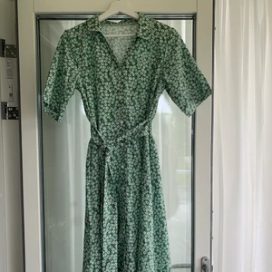 Grön blommig klänning  - Säljer denna fina sommarklänning för att den blivit för liten. Hoppas den kan hitta ett nytt hem.   Storlek saknas men jag skulle säga att den passar som en Medium. 