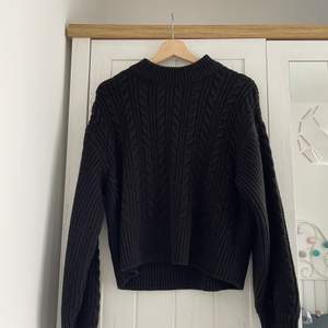 black sweater from Monki with cable-knit details.