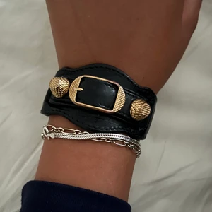 Balenciaga armband - Säljer mitt balenciga armband i svart med guld detaljer. Armbandet finns inte kvar att köpa, vilket gör det mycket unikt! Låda och tags tillkommer såklart!❤️‍🔥