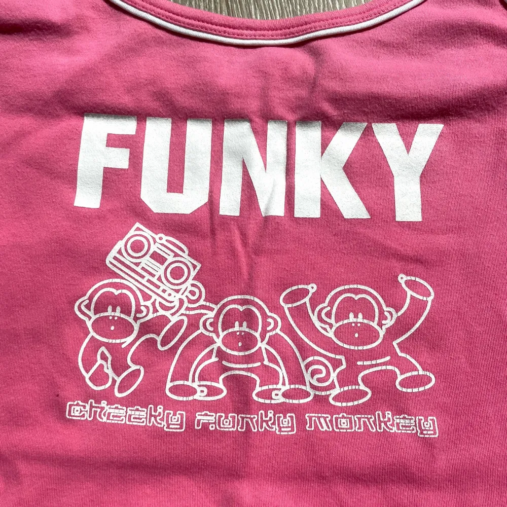 Så sött rosa linne med ”Cheeky Funky Monkey” slogan och tre små animerade apor från 00-talet!💕 Fin croppad passform! Storlek M men är inte förstor på mig som är en Xs! I perfekt skick!💋. Toppar.