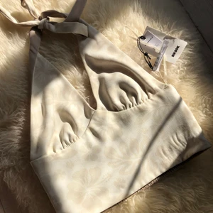 Topp - Helt ny, prislappen kvar. Köpte för 300kr. Går att använda både in och ut, då insidan bara är beige och utsidan krämvit med blommor på