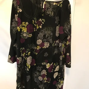 Tunika/klänning  - Fin tunika/klänning med svart botten med mönster i grå/vit/lila/gul. Obetydligt använd. Stl 40. Frakt betalas av köparen.