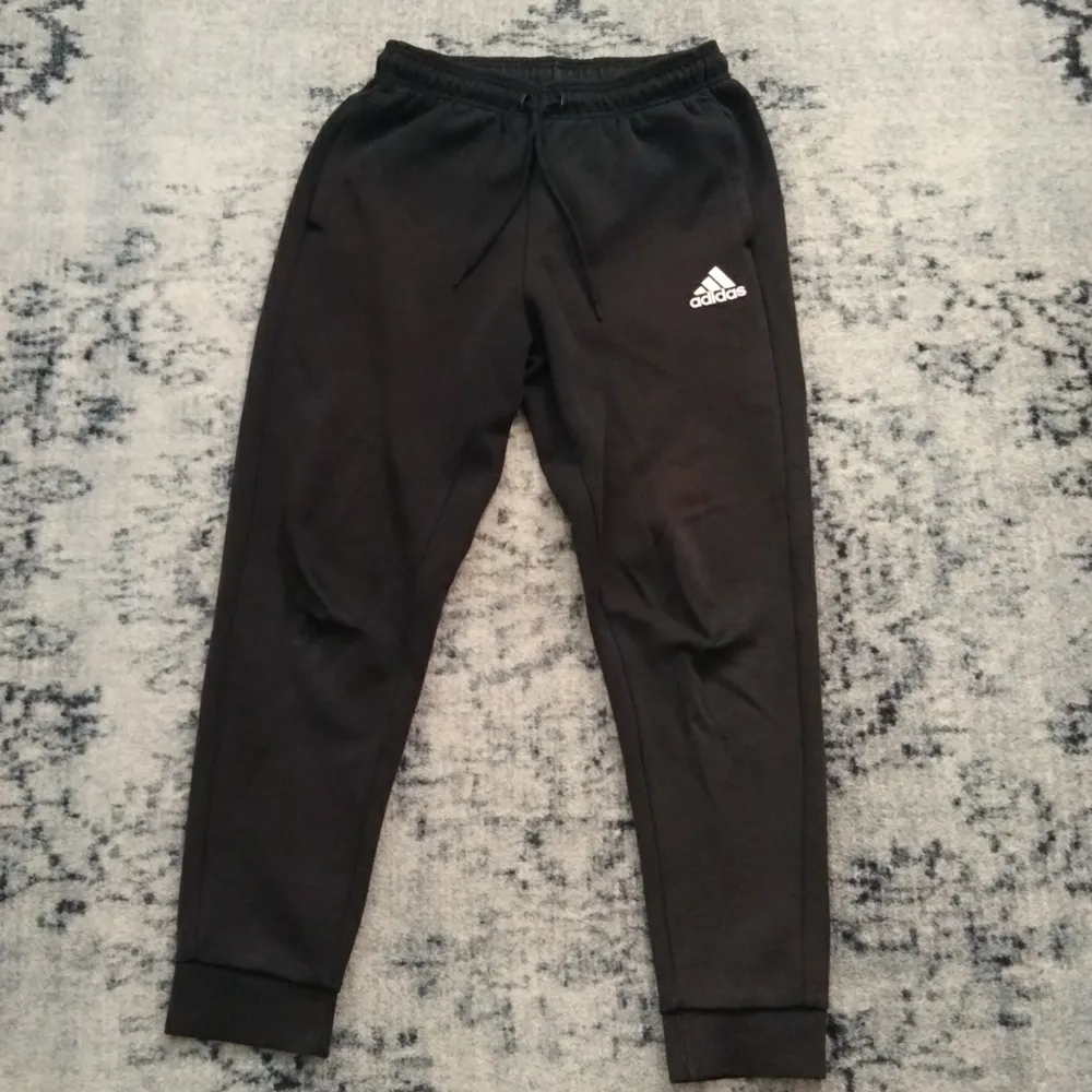 Svarta Adidasbyxor, ganska slitna på vänster och höger knä. Har tappat lite färg och är använda.. Jeans & Byxor.