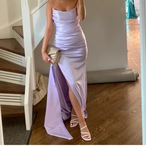Festklänning - Ljuslila satinklänning i storlek 36. Endast använd en gång och är i gott skick. Pris 2500kr. Kan mötas upp i Södertälje eller  fraktas med postnord, och kunden står för frakten🥰