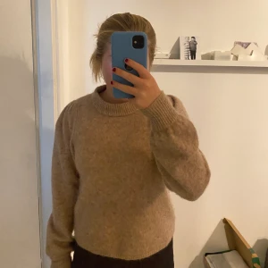 Stickad tröja!! - En super fin beige stickad tröja från neo noir. Den är super varm och inte alls stickig och har en snygg detalj vid armarna som ej syns men gör tröjan lite snyggare. Den är perfekt nu till vintern/ hösten att ha som en vardagströja eller fintröja! 