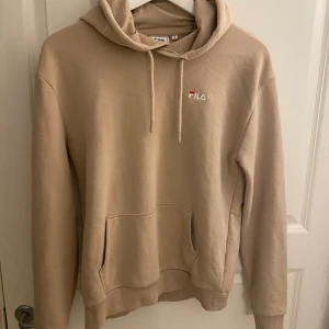 Hoodie - Beige hoodie från fila med tryck på bröstet, fint skick, sparsamt använd, storlek Small.