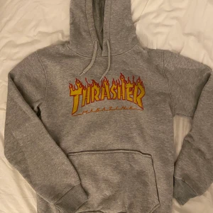 Thrasher Hoodie - Säljer en grå Thrasher hoodie, perfekt för streetwear och skater-stil. 