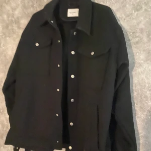 Overshirt  - Hej, Säljer en snygg Svart Overshirt i skönt material.  Köpte den i höstas, användt några gånger. Obs! Knappen längst ner är lite dålig.