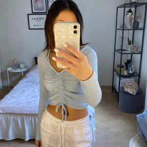 Blå tröja med snörning - Långärmad ribbad ljusblå tröja med snörning man kan justera själv. Kan mötas upp eller frakta.