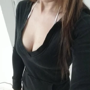 En figurnära hoodie - En svart figurnära hoodie i bra skicka. Har sliten design på urringningen.