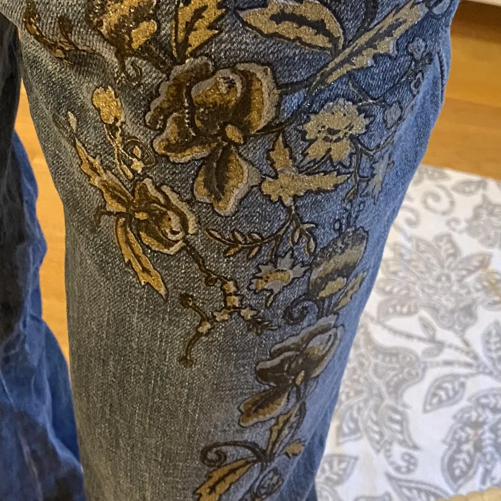Jeans med guld och silver blomma på låren. . Jeans & Byxor.