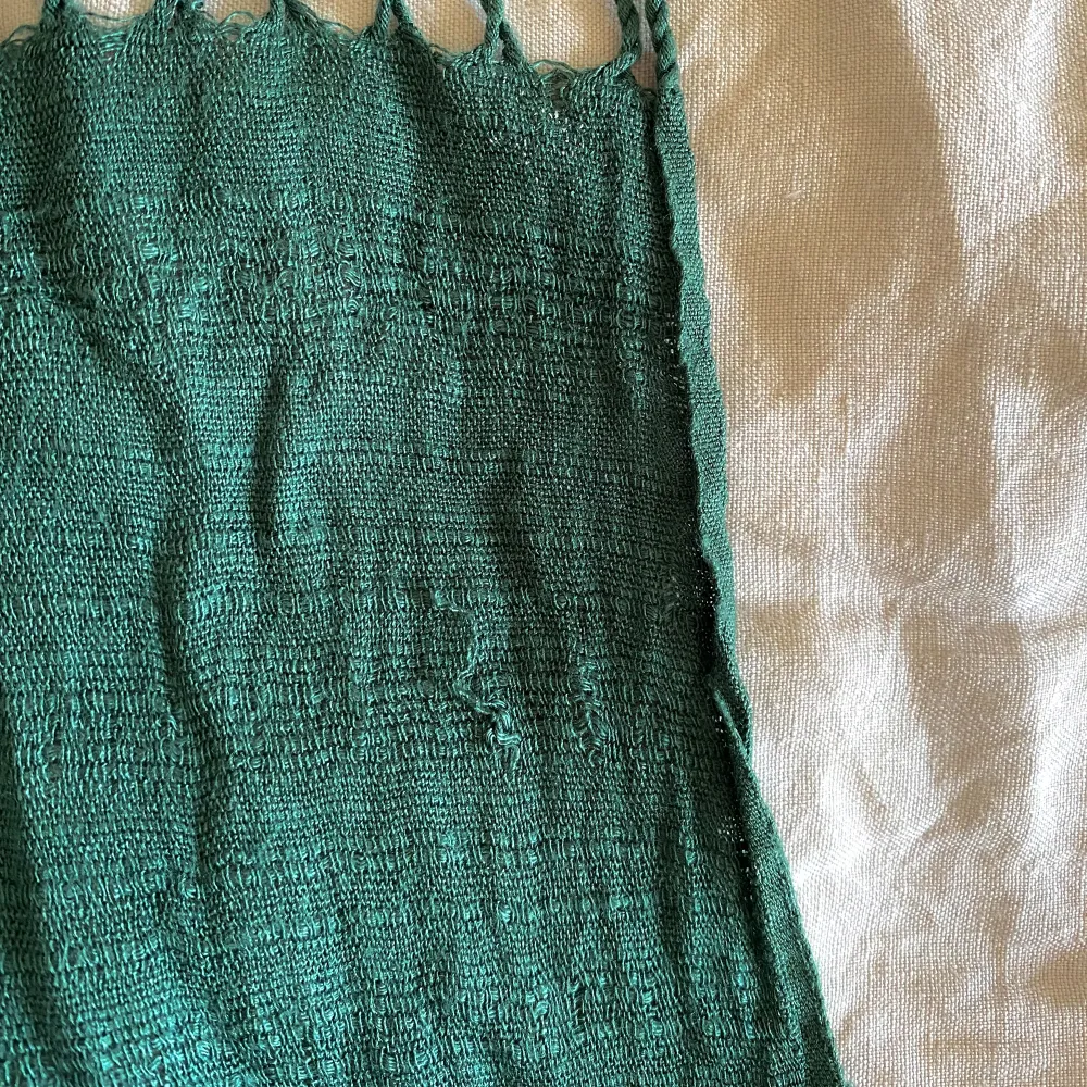 En klargrön sidensjal med fransar.  Den är köpt på en marknad i Thailand för några år sedan. Men det finns inte någon material-lapp kvar så jag kan inte garantera att det är 100% Siden.  Materialet är lätt och fint.   Det finns några små revor i tyget. . Övrigt.