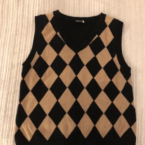 Stickad väst  - Stickad svart beige rutig väst. Strlk 42. 