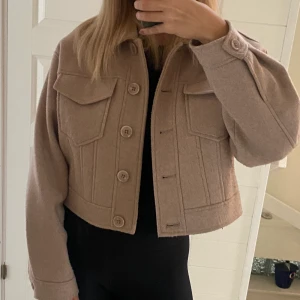 NA-KD Jacka - Superfin beige Croppad kappa/jacka från NA-KD. Köpt för något år sen men kommer tyvärr inte till användning längre💕 strl 38, köparen står för frakten💕