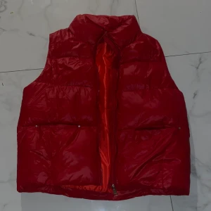 Röd puffer väst  - Röd väst i jätte mysigt material. Passar en M bäst men även S. 
