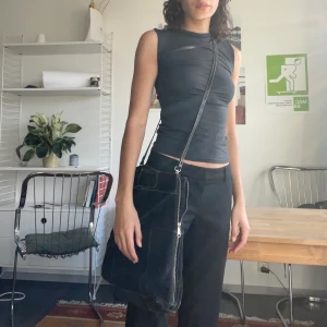 Äkta mocka svart väska med dragkedja - Superfin svart mocka (lite grå ton) går att bära i handtag eller över axeln. Dragkedjan går att dra ner vilket gör väskan större