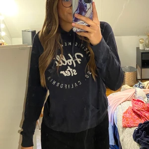 Hollister hoodie marinblå - Väl använd hoodie från hollister! Texten är silver glittrig! Liten i storleken.