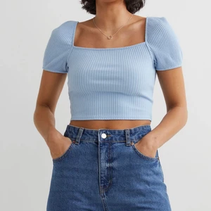 Ribbad topp - Kort topp i ribbad trikå. Den har figurnära passform, med fyrkantig halsrigning. Den har kort puffärm och är i en väldigt fin blå färg. Den är i storlek L och är helt ny. Endast testad. Säljs för 80 kr+frakt