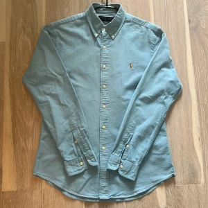 Ralph Lauren skjorta - En skitsnygg ljusblå Ralph Lauren skjorta i storlek L. Den har blivit väl omhändertagen, dock har den inte använts mycket så skicket är fortfarande mycket bra på den. Nypris: 1500, mitt pris: 550 kr.