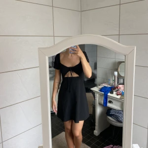 En svart kort klänning  - En svart kort klänning med öppning precis under bröstet. Jag är 170 cm och klänningen kommer från hm. 