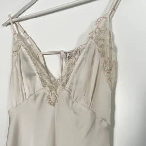 Spetsklänning  - Långklänning i spets i mycket bra skick, materialet är satin och faller väldigt fint på kroppen! Låg i ryggen och spets på både fram och baksida