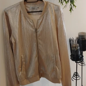 Guld/ silver färgad tunn jacka med dragkedja storlek m fickor på sidan - Silver/guldfärgad tunn jacka med dragkedja och fickor på sidan storlek m