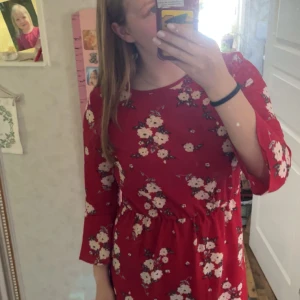 Rod klänning  - Röd klänning med vita blommor, från H&M i storlek 40. Använd om inga defekter eller fläckar, inte så stretchigt material, har trekvarts armar och är lite kortare än knälång.  Skriv för mer info eller bilder! 💕