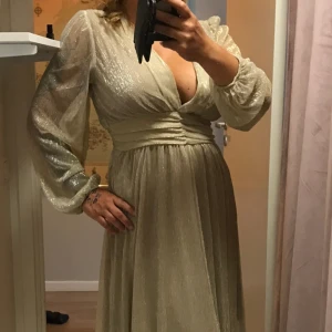 Långklänning fest/bröllop - Guld/beige långärmad långklänning, med underkjol str M/L Otroligt fin !!  Men är lite för stor för mig.  Köpt på Dressing Room  Maj månad. nypris 899kr  60% polyester  40% viscose  Prislapp kvar  Finns i Floda / Lerum