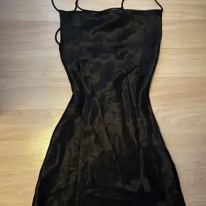 Svart satin klänning med snörning i ryggen från Gina tricot i storlek 32