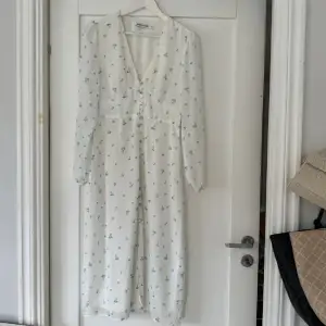 Säljer min vita klänning med blåa blommor på från Adoore i modellen Paris🩵den har  tråddragningar på framsidan, skriv för bilder🩵den är i storlek 36
