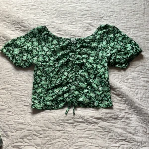 Blus - Jättefin lite kortare grönblommig blus. Mycket stretch finns i ryggen men sitter jättefint. Denna fina blus är även i jättebra skick