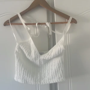 Vit tröja med snören  - En justerbar vit tröja från Zara. En ribbad vit tröja med snören vid nacken som går att justera som man vill. Öppen rygg